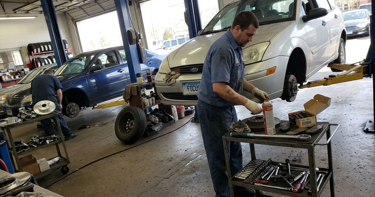 Technician comparing an old rotor to a new one on a bench, New Britain shop, candid